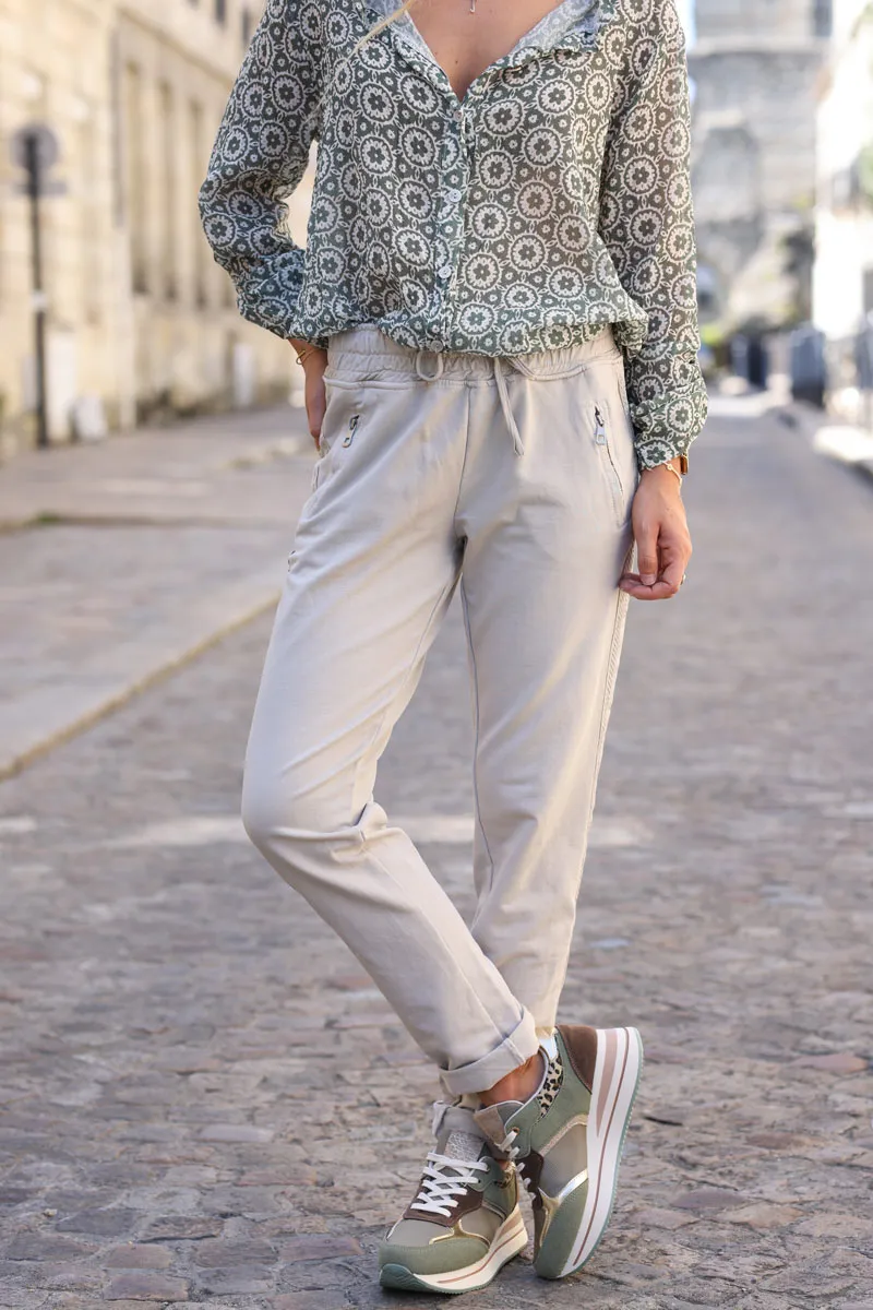 Jogging beige en coton ceinture élastique et poches zips liseré broderie chevrons